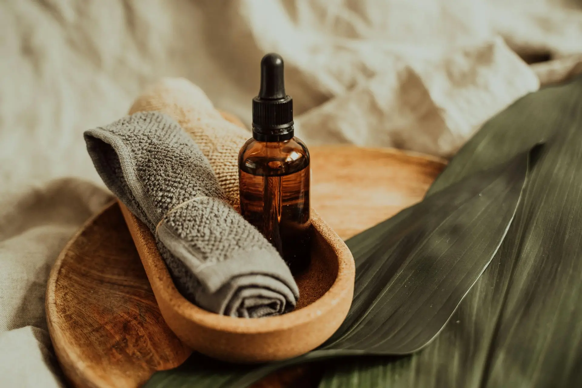 Essential oil and towel setup on wooden tray.