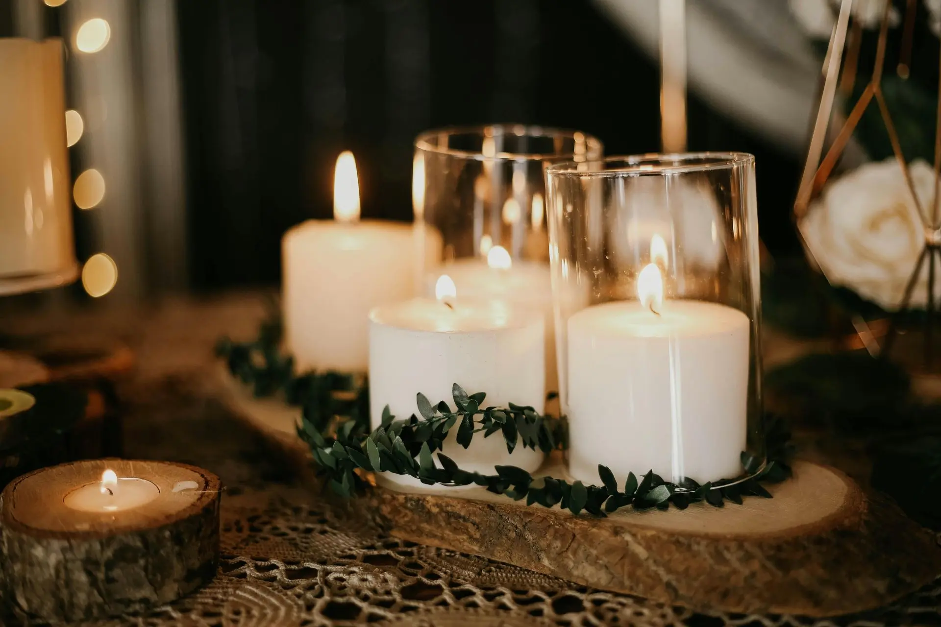 Lit soy candle beside dried flowers and soft textiles.